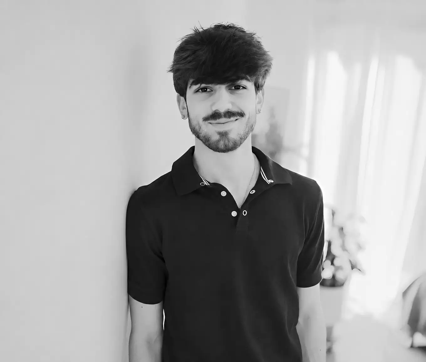 Young smiling man leaning against wall